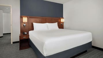 A hotel room with a large bed, two bedside tables with lamps, and a door to another room.