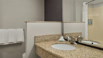 A bathroom with a granite countertop sink, a mirror, and a towel rack.