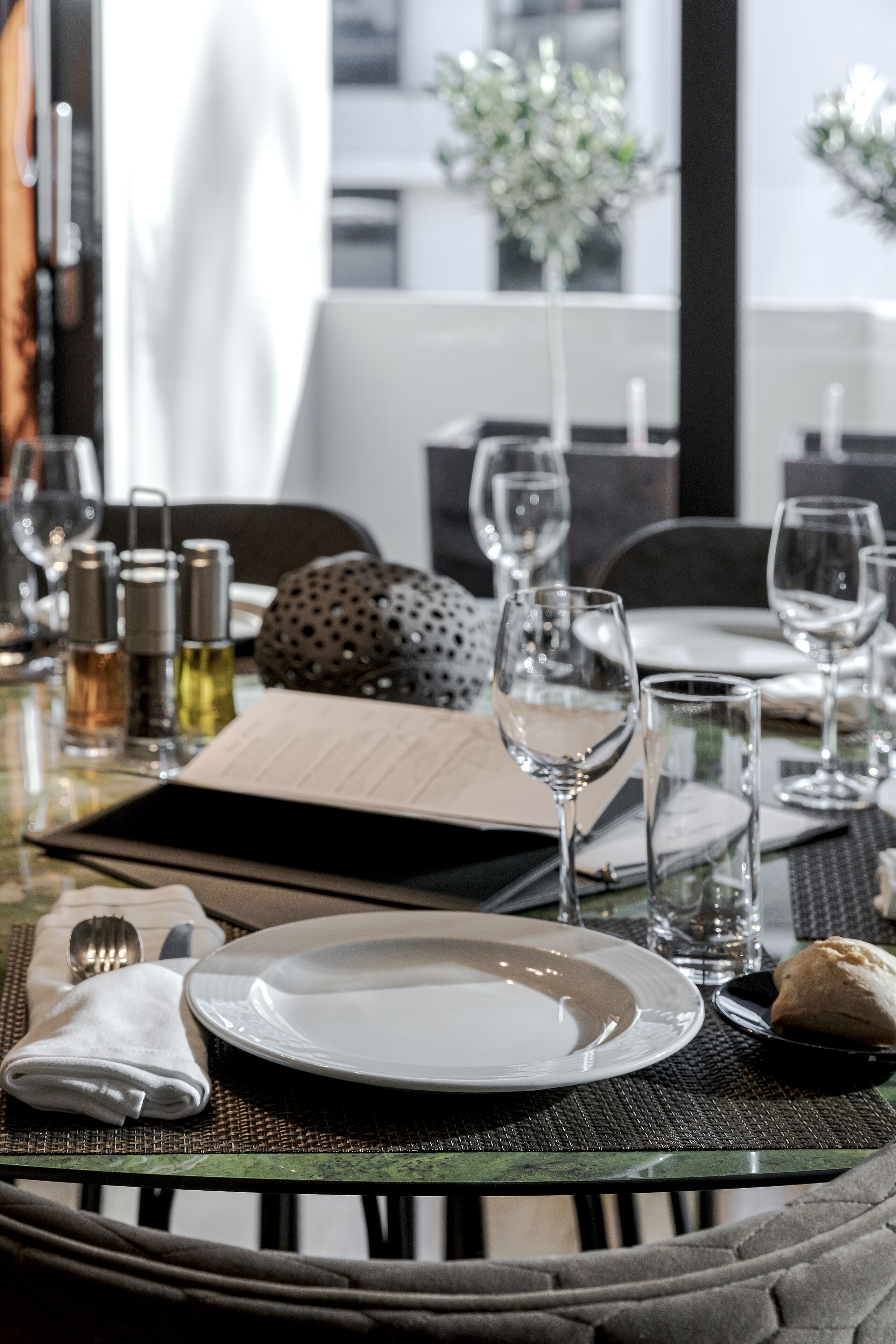 A dining table set with plates, glasses, and cutlery, with a bottle of water and a napkin on the table.