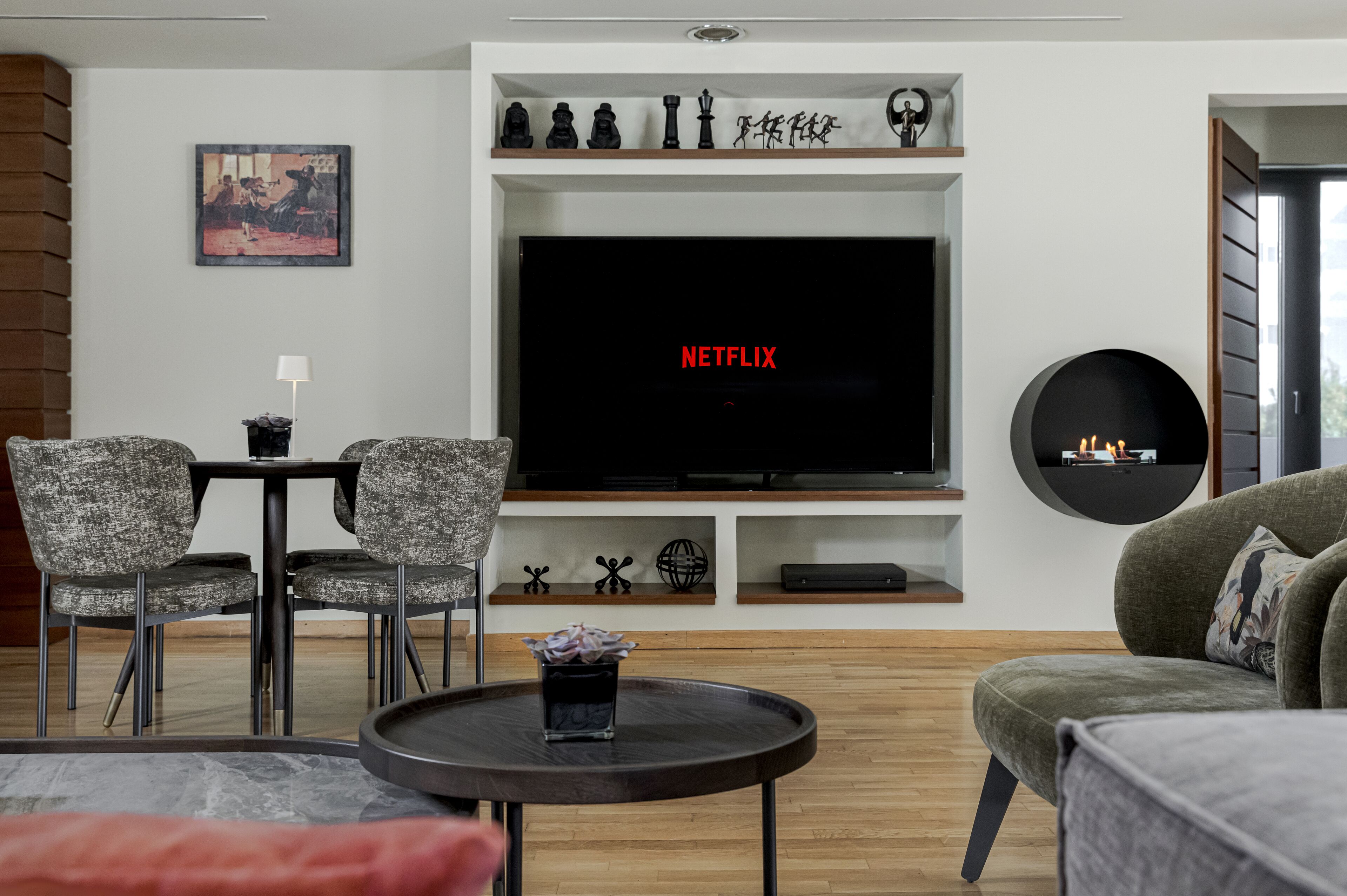 Un salon moderne doté d’un téléviseur à écran plat, d’une cheminée, d’un coin repas et d’une table basse.