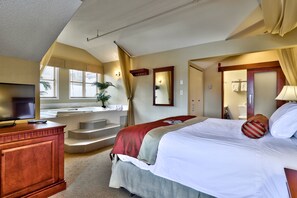A hotel room with a bed, a TV, a bathroom, and a staircase. - Sun Peaks Lodge (Sun Peaks)