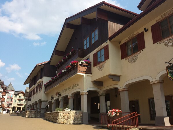 Un hotel de estilo arquitectónico europeo tradicional, con balcones adornados con jardineras y un cartel que dice "GOLD PEAKS LODGE".
