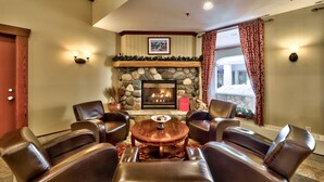 A cozy room with leather chairs, a stone fireplace, and a view of a building outside.