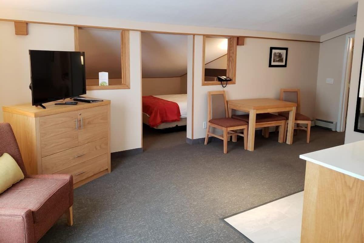 A compact room with a bed, a desk, a chair, a television, and a small cabinet.