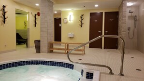 A hotel bathroom with a hot tub, shower area, and a bench.