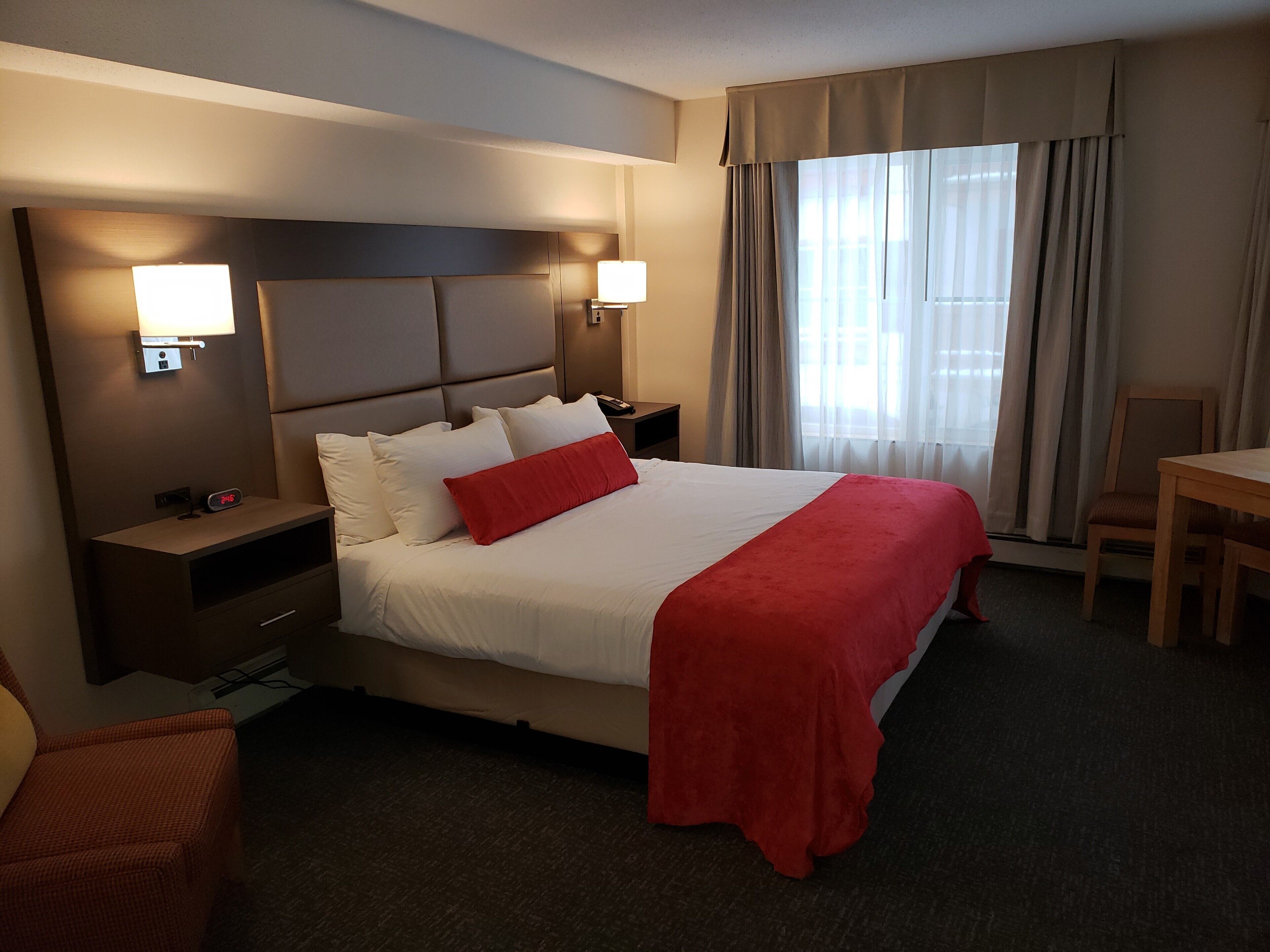 A hotel room with a large bed, two bedside tables, a desk, and a chair.