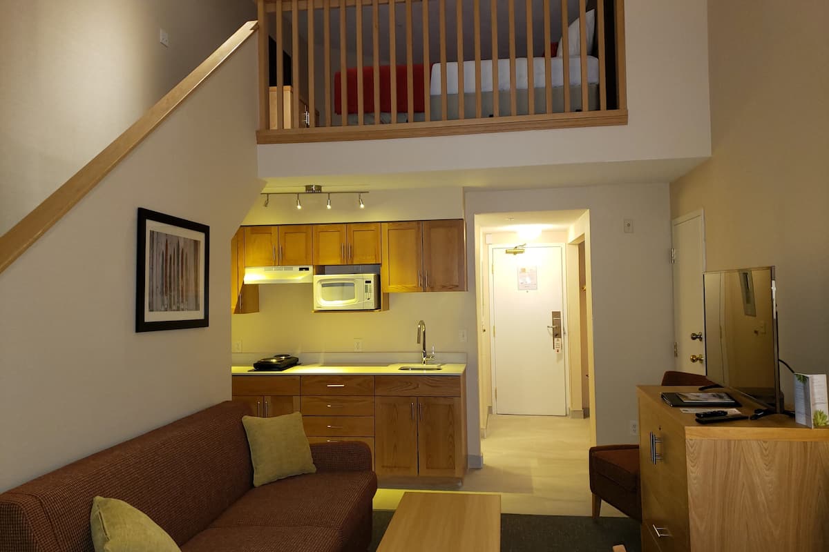 A compact living space with a kitchenette, a dining area, and a bedroom with a loft.