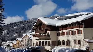 A snow-covered building with a balcony and a sign that reads "AUS PEAK-ÖGE".