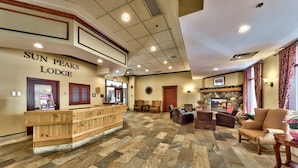 A reception area with a wooden counter, stone flooring, and a fireplace.