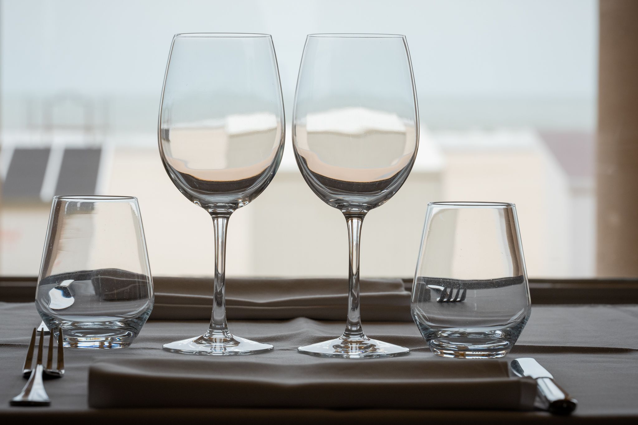 Tres copas de vino sobre una mesa, con vistas a edificios a través de una ventana.