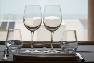 Tres copas de vino sobre una mesa, con vistas a edificios a través de una ventana.