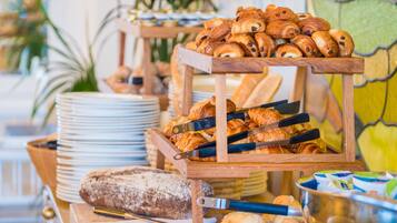 Un buffet proposant une variété de produits de boulangerie, notamment des croissants et du pain, présentés sur des présentoirs en bois.