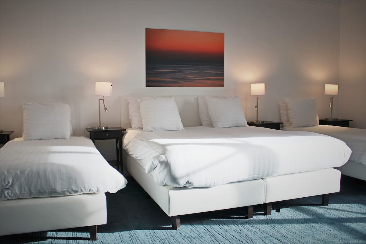 A hotel room with a large bed, two bedside tables, and a wall-mounted painting.