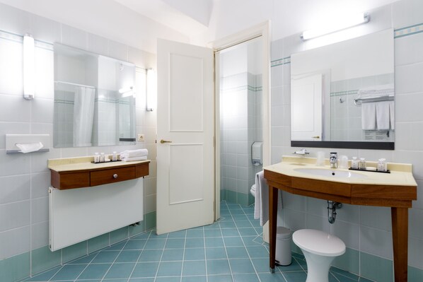 A modern bathroom with two sinks, a toilet, and a shower area. - Thermae Palace Hotel (Ostend)