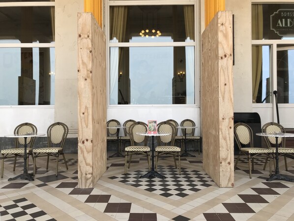 An outdoor cafe with checkered flooring, wicker chairs, and tables. - Thermae Palace Hotel (Ostend)