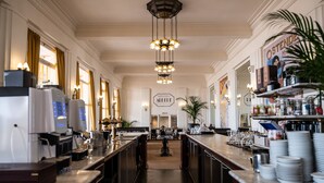 A spacious bar area with a long counter, multiple light fixtures, and a central decorative element. - Thermae Palace Hotel (Ostend)