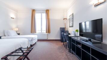 Habitación de hotel con dos camas, televisor, escritorio y ventana con cortinas.