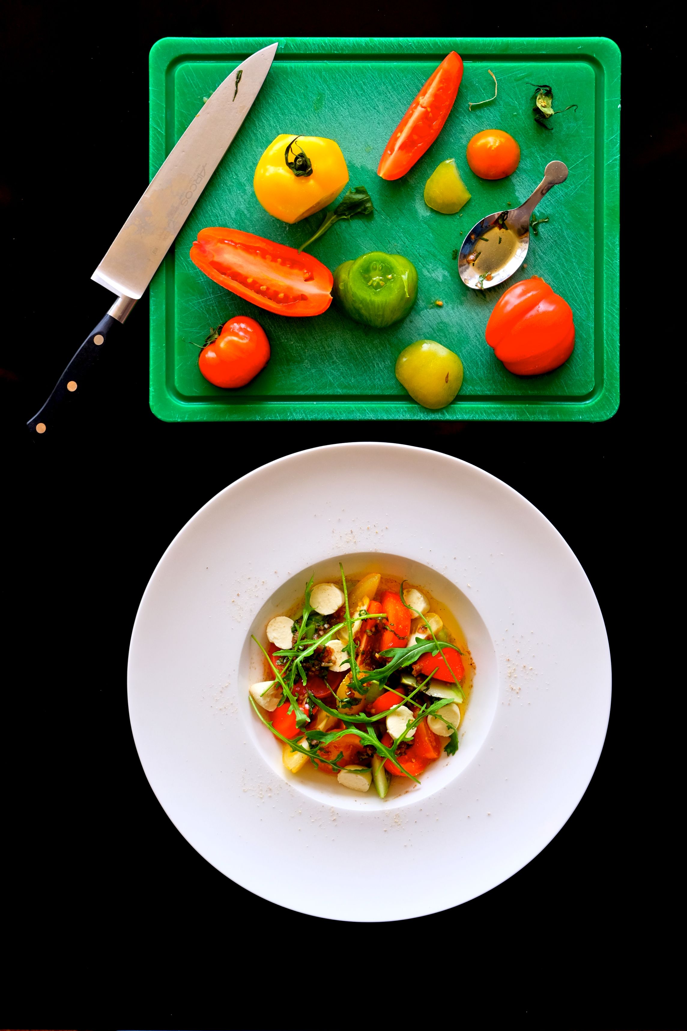 A white plate with a salad on a black table.