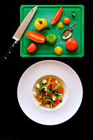 A white plate with a salad on a black table.