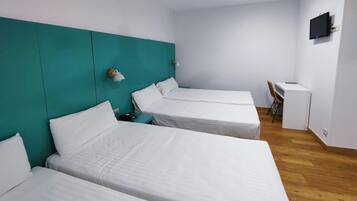 Ein Zimmer mit drei Einzelbetten, einem Schreibtisch und einem Stuhl.