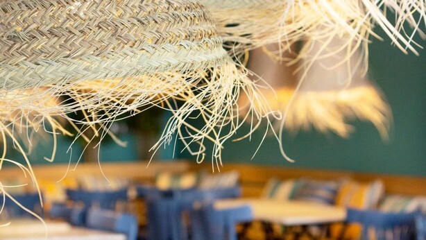 A restaurant interior with round tables and chairs, and hanging woven light fixtures. - Yomo Hostal BCN Port (Barcelona)