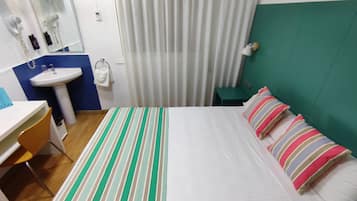 A hotel room with a bed, a desk, a sink, and a mirror.