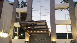 A modern hotel building with a prominent entrance, large windows, and a well-lit facade. - Villaggio Hotel Boutique (Mendoza)