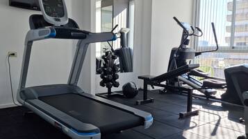 Et fitnessrum med løbebånd, motionscykel og håndvægte.