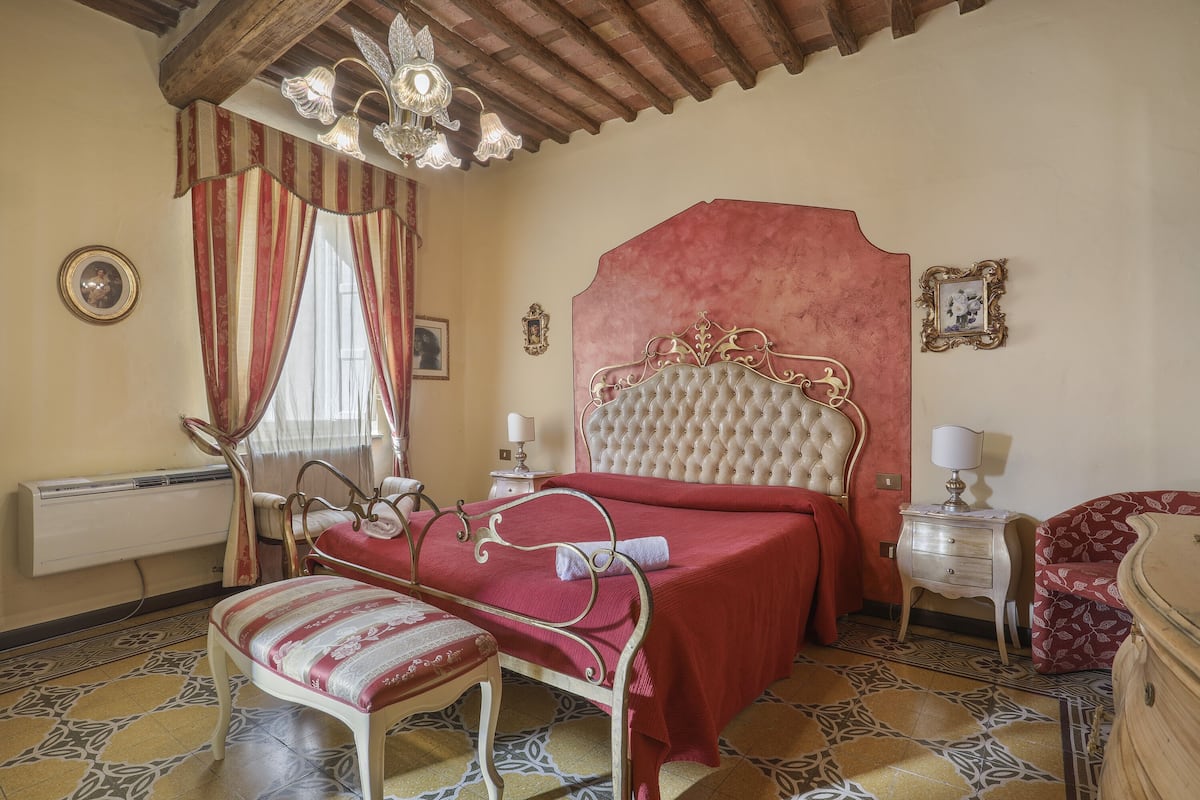 Een slaapkamer met een groot bed, een nachtkastje, een stoel en een dressoir.