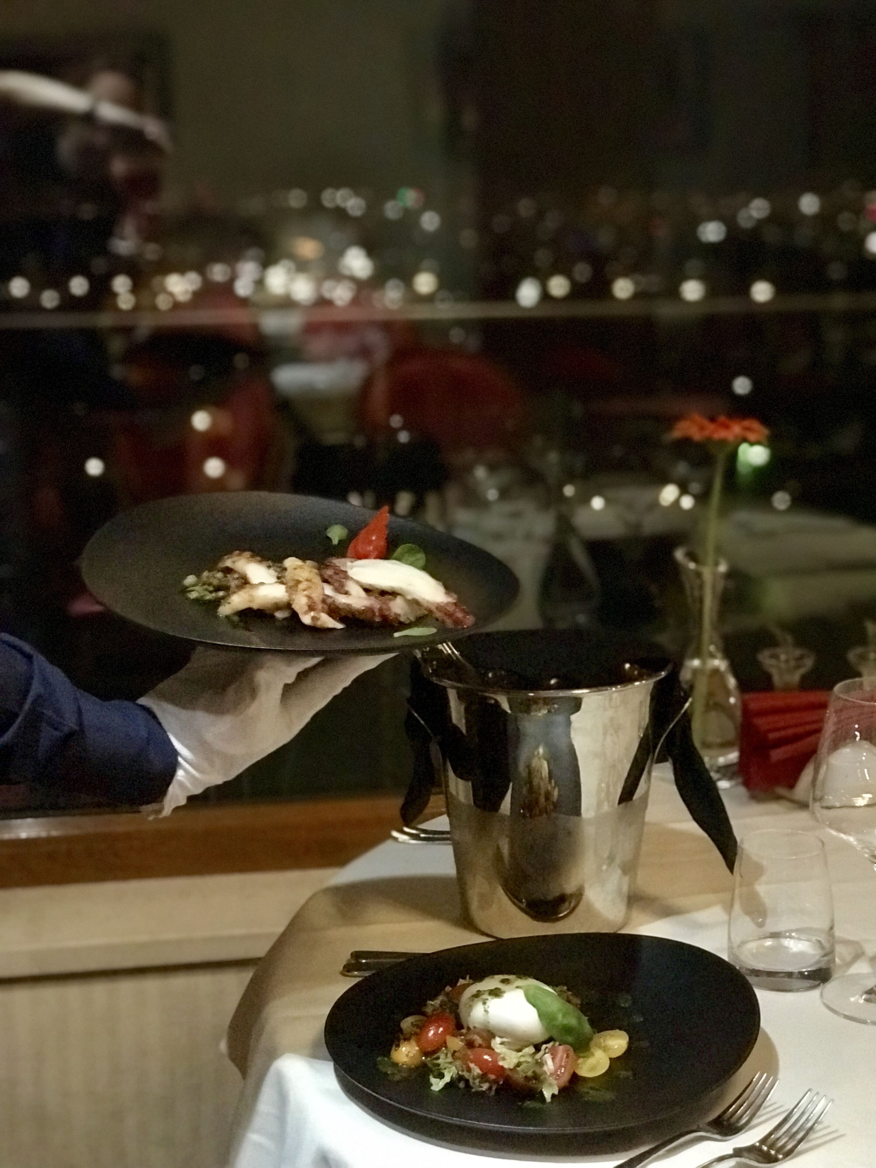 Et spisebord med mad på en tallerken, en kande og en vase med en blomst.