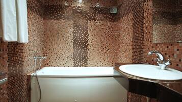 Un baño con bañera, lavamanos y paredes de azulejos.