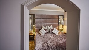 Quarto com cama grande, cabeceira, mesas de cabeceira e espelho.