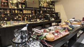 A buffet with various food items and a selection of wine glasses and bottles.