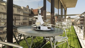 A rooftop terrace with a round table, chairs, and a bottle of wine. - Carat Boutique Hotel (Budapest)