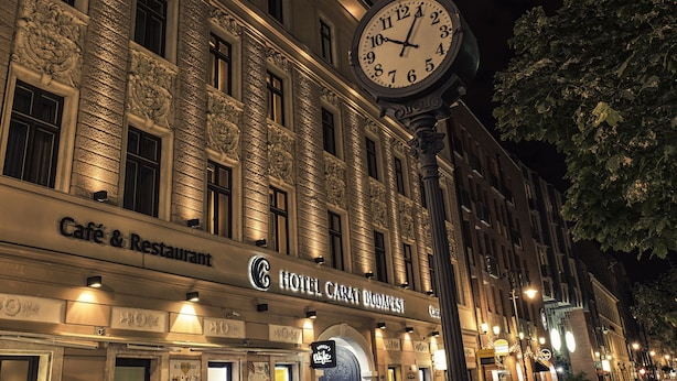 A building with a clock, a sign for 'Hotel Carat Budapest', and a 'Café & Restaurant' sign. - Carat Boutique Hotel (Budapest)