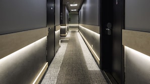 A hotel hallway with a patterned carpet, dark walls, and doors on both sides. - Carat Boutique Hotel (Budapest)