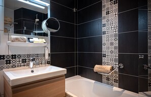 A modern bathroom with a white sink, a mirror, and a bathtub. - Hotel Delavigne (Paris)