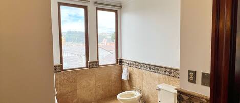 Une salle de bain avec deux toilettes, un lavabo et une douche.