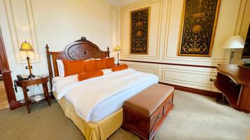 Une chambre d’hôtel avec un grand lit, deux tables de chevet avec des lampes, un banc en bois et des panneaux décoratifs sur les murs.
