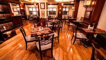 A restaurant with wooden floors, multiple dining tables, and chairs.