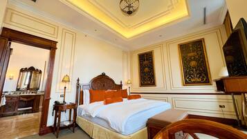 A hotel room with a large bed, a wooden desk, a mirror, and a chandelier.