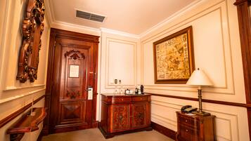 Un pasillo con una puerta de madera, un escritorio con una lámpara y un mapa enmarcado en la pared.