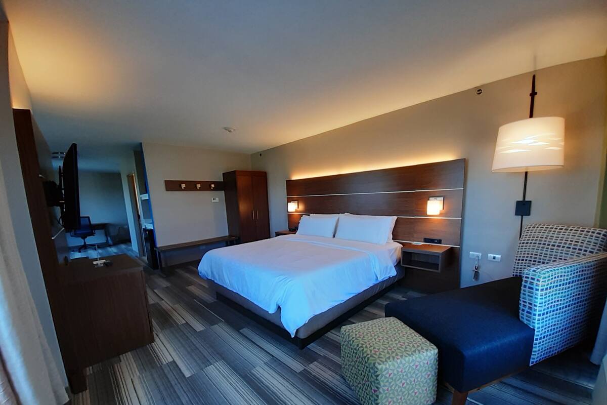 A hotel room with a large bed, bedside tables, a TV, a desk, and a chair.