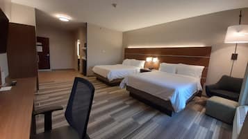 Habitación de hotel con dos camas, un escritorio, una silla y una lámpara.