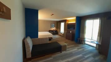 Une chambre d’hôtel avec un lit, un canapé, un bureau et une télévision.