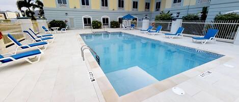A swimming pool with lounge chairs and a building in the background.