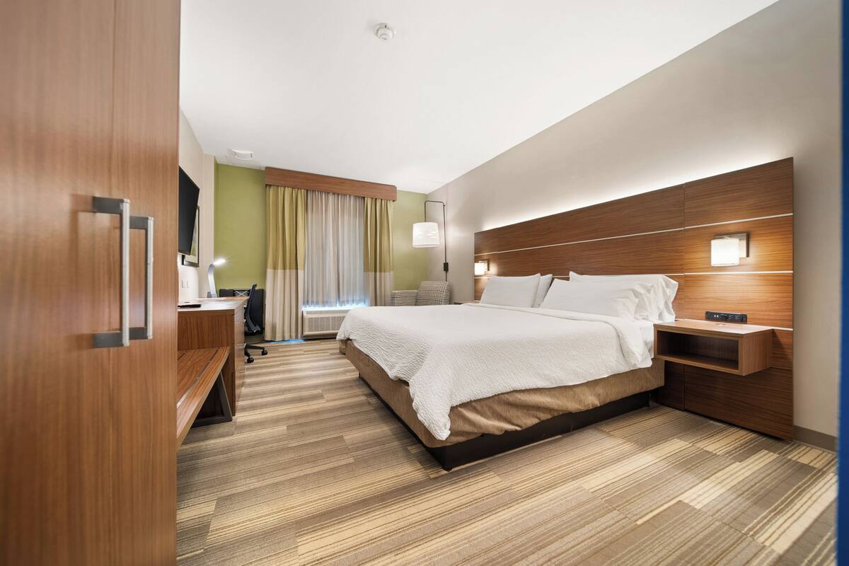 A hotel room with a bed, bedside tables, a desk, and a chair.