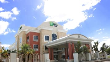 Een Holiday Inn Express gebouw met een beige gevel, rode accenten en een overdekte ingang.