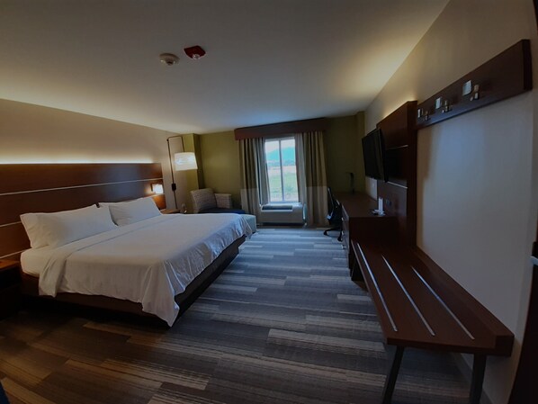 A hotel room with a large bed, a desk, a TV, and a window with curtains. - Holiday Inn Express Hotel & Suites Trincity Trinidad Airport by IHG (Piarco)