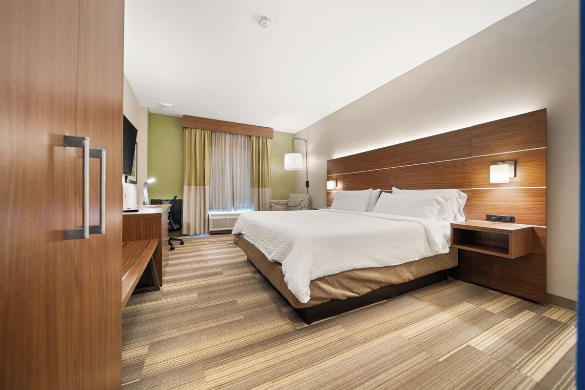 A hotel room with a bed, bedside tables, a desk, and a chair.